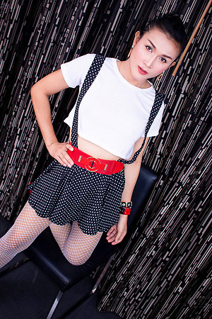 Ladyboy Ice is wearing a skirt with suspender straps over a little white blouse with high heels.